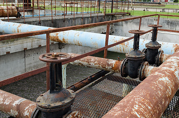 Image showing Rusty big tap and pipes and water treatment liquid 