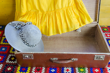 Image showing gray femalee hat suitcase yellow dresses fragment