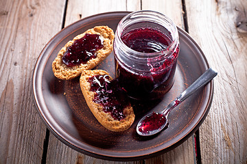 Image showing black currant jam in glass jar and crackers