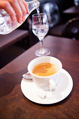Image showing Cup of espresso and pouring water