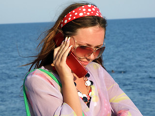 Image showing The beautiful girl talks by a mobile phone on the sea