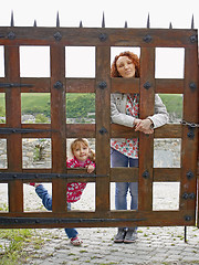 Image showing Woman and a small girl behind a wooden gate