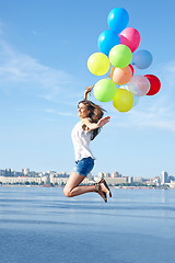 Image showing Happy young woman jumping with colorful balloons