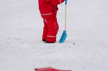 Image showing child stand with snow shovel in waterproof wear 