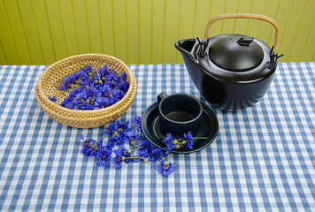 Image showing freshly picked cornflower on basket clay tea set 