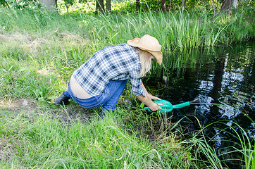 Image showing Farm gardener girl draw water from pond 