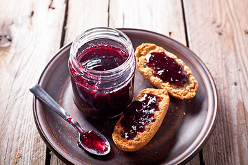 Image showing black currant jam in glass jar and crackers