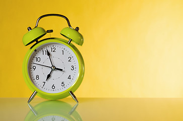 Image showing Green alarm clock, close up. A yellow background