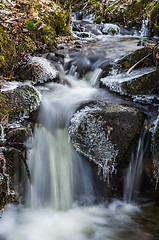 Image showing Small waterfall with icicles and ice close up, spring.