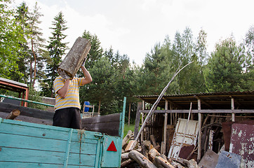 Image showing worker man unload tree logs firewood from trailer 