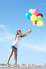 Image showing Happy young woman flying away with balloons