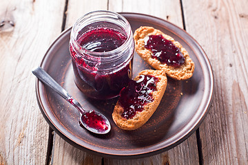 Image showing black currant jam in glass jar and crackers