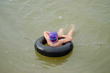 Image showing girl with diving hat floating on  tire in water  