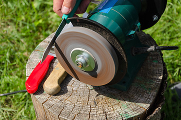 Image showing Hand sharpening knives with electric grinder tool 