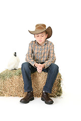 Image showing Country boy sitting on lucerne bale