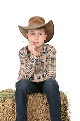 Image showing Cowboy sitting on hay bale