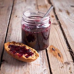 Image showing black currant jam in glass jar and cracker