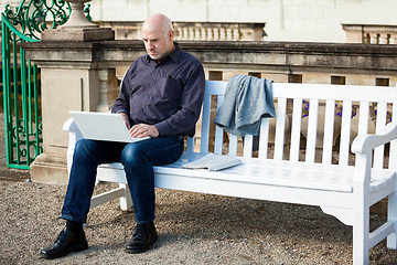 Image showing Man sitting on a bench using a laptop