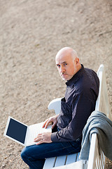 Image showing Man sitting on a bench using a laptop