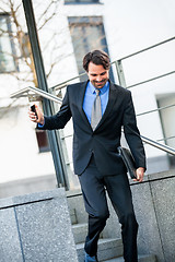 Image showing Smiling businessman walking down stairs