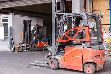 Image showing Small orange forklift parked at a warehouse