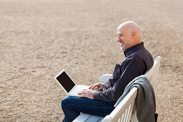 Image showing Man sitting on a bench using a laptop