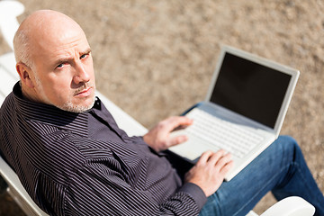 Image showing Man sitting on a bench using a laptop