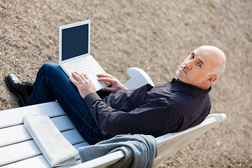 Image showing Man sitting on a bench using a laptop