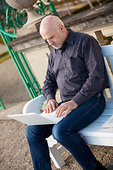 Image showing Man sitting on a bench using a laptop