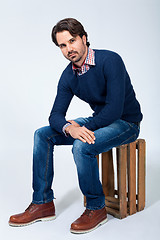 Image showing Handsome young man sitting on a wooden box