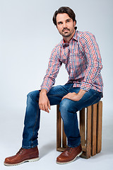 Image showing Handsome young man sitting on a wooden box