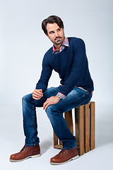 Image showing Handsome young man sitting on a wooden box