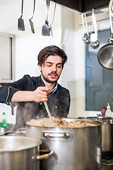 Image showing Chef stirring a huge pot of stew or casserole