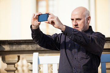 Image showing Man taking a photograph with his mobile