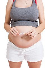 Image showing Pregnant woman breaking a cigarette in two