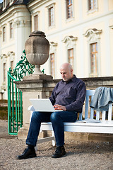 Image showing Man sitting on a bench using a laptop