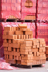 Image showing Red clay bricks stacked on pallets