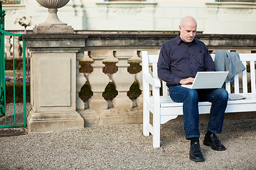 Image showing Man sitting on a bench using a laptop