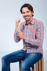 Image showing Handsome young man sitting on a wooden box