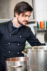 Image showing Chef stirring a huge pot of stew or casserole