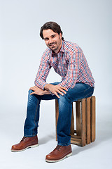 Image showing Handsome young man sitting on a wooden box