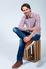 Image showing Handsome young man sitting on a wooden box