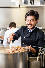 Image showing Chef stirring a huge pot of stew or casserole