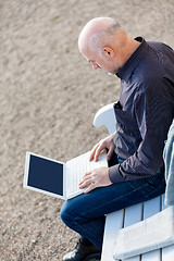 Image showing Man sitting on a bench using a laptop