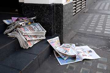 Image showing Tabloid newspapers abandoned in a shop doorway