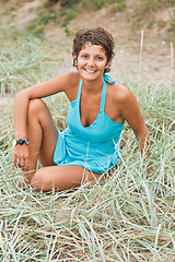 Image showing brunet woman in blue sitting in a grass