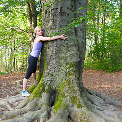 Image showing Young woman hugging a tree.