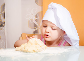 Image showing baby girl in cook role molds from dough