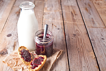 Image showing black currant jam in glass jar, milk and crackers