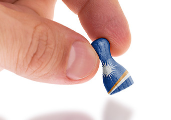 Image showing Hand holding wooden pawn, flag painting, selective focus